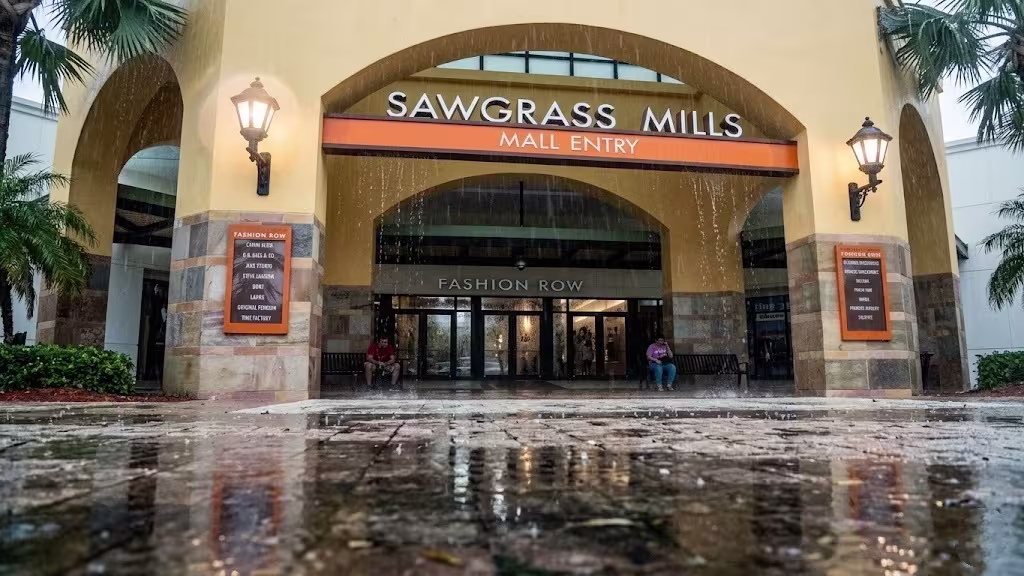 Exterior entrance of a modern shopping mall showing interior through glass facade